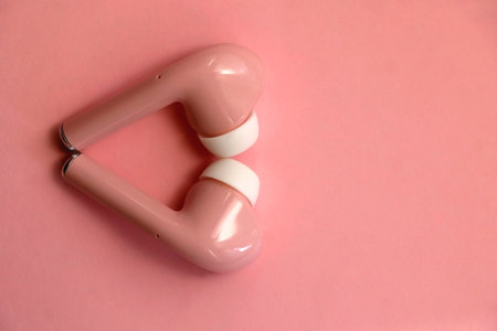 Pink wireless  earphones on pink background. Flat lay.