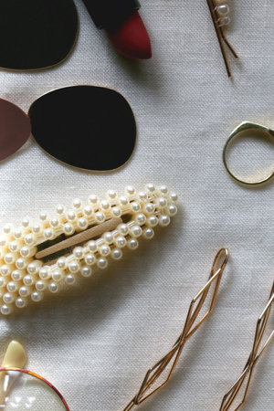 Various gold jewelry, personal accessories and beauty products on neutral background. Flat lay.