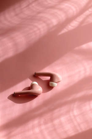 Pink earphones on pink background. Selective focus.