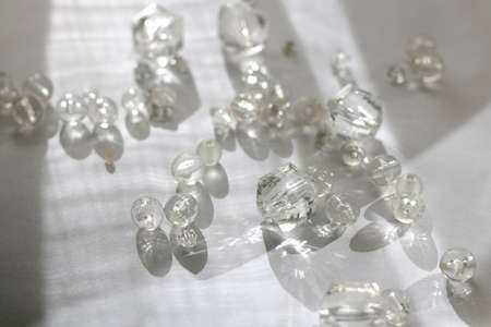 Various transparent beads on white background, illuminated by sunlight and reflectiing light....
