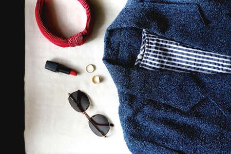 Blue jacket, striped shirt, round sunglasses, red hair band, red lipstick and gold rings. Flat lay.の写真素材