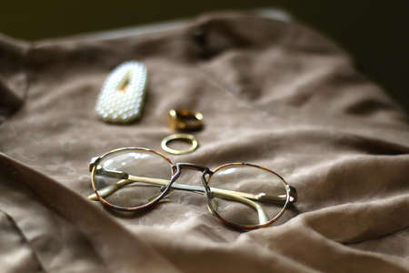 Brown vintage blouse, retro eyeglasses, pearl hair clip and gold rings. Selective focus.の写真素材