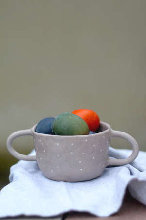Ceramic bowl filled with painted Easter egss in jewel tones. Selective focus.