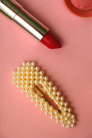 Pearl hair clip, red lipstick and pink blush on bright pink background. Flat lay.の写真素材
