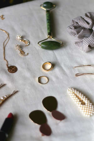Various gold jewelry, personal accessories and beauty products on neutral background. Selective focus.の写真素材