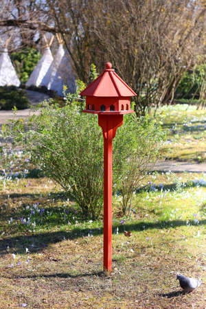 Cute red birdhouse in the beautiful park. Early spring day. Selective focus.の写真素材