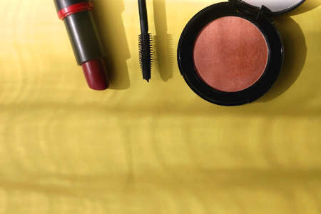 Lipstick, mascara and blush on bright yellow background. Flat lay.の写真素材