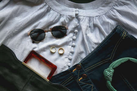 Striped blouse, denim skirt, sunglasses, gold rings, fashionable bag and green headband. Flat lay.の写真素材