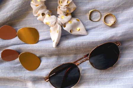 Blue linen shirt, sunglasses, white scrunchie, gold rings and fashionable earrings. Flat lay.の写真素材