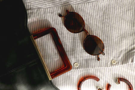 Striped shirt, leather bag, brown sunglasses and tortoiseshell pattern sunglasses. Flat lay.の写真素材