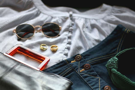 Striped blouse, denim skirt, sunglasses, gold rings, fashionable bag and green headband. Selective focus.の写真素材