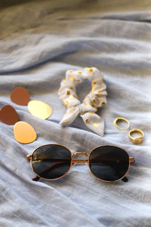 Blue linen shirt, sunglasses, white scrunchie, gold rings and fashionable earrings. Selective focus.の写真素材