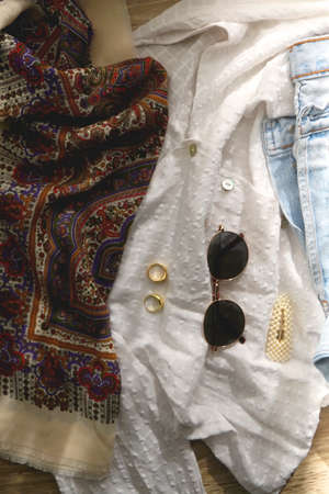 Vintage denim pants, white blouse, boho scarf, round sunglasses, gold rings and pearl hair clip. Flat lay.の写真素材