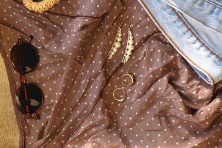 Brown polka dot blouse, vintage mom jeans, straw bag, round sunglasses, gold rings and pearl hair...