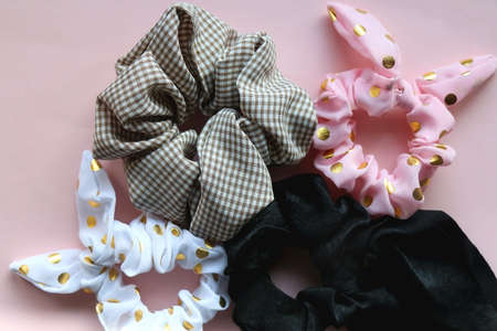 Various cute scrunchies on pastel pink background. Flat lay.