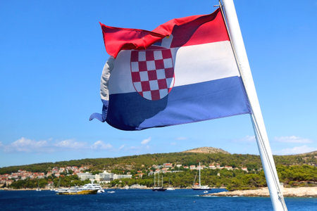 Flag of Croatia on a boat, blowing in the wind. Town Hvar on island Hvar is in the background. Selective focus.の写真素材