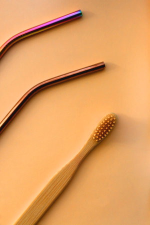 Reusable metal straws, wooden toothbrush, reusable safety razor and mesh bag on neutral background....