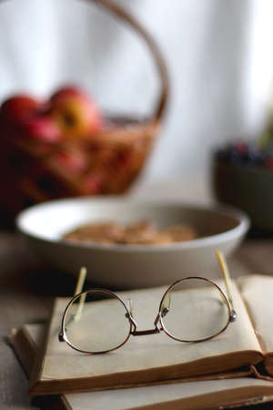 Bowl of strawberries and blueberries, open books with reading glasses, plate of chocolate chip...
