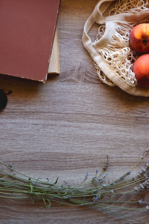 Sunglasses, vintage books, reusable mesh bag with fresh peaches, seashell and lavender flowers on wooden background Boho and rustic summery details, flat lay.の写真素材