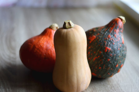 Two Hokkaido pumpkins and one butternut squash on wooden table. Selective focus.の写真素材