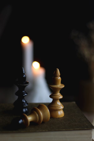 Stack of vintage books, cup of tea or coffee, lit candles, reading glasses and chess pieces on wooden table. Dark academia concept. Selective focus.の写真素材
