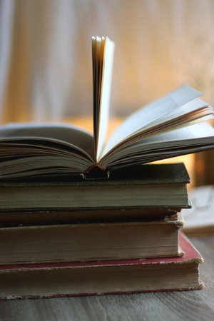 Plate of chocolate chip cookies, stack of vintage books, reading glasses, cup of tea or coffee, lit...