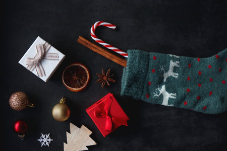 Christmas stocking filled with small presents, sweets and various decorations. Dark background, flat lay.の写真素材