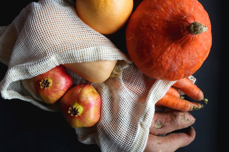 Various healthy autumnal food in reusable mesh bags. Top view, dark background.