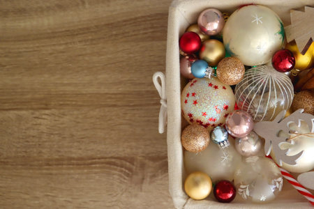 Wicker basket filled with various colorful Christmas decorations on wooden table. Top view.の写真素材