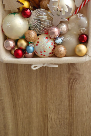 Wicker basket filled with various colorful Christmas decorations on wooden table. Top view.の写真素材