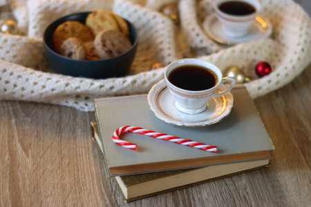 Cups of tea or coffee, bowl of cookies, soft blanket, lit candles, books and various Christmas decorations on the table. Selective focus.の写真素材