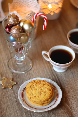 Two types of cookies, cups of tea or coffee, various Christmas decorations and lit candles. Cozy Christmas atmosphere at home. Selective focus.の写真素材
