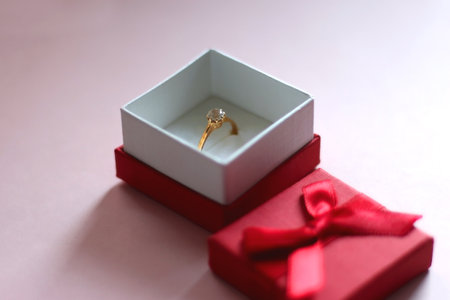 Engagement ring in elegant red box. Pink background, selective focus.