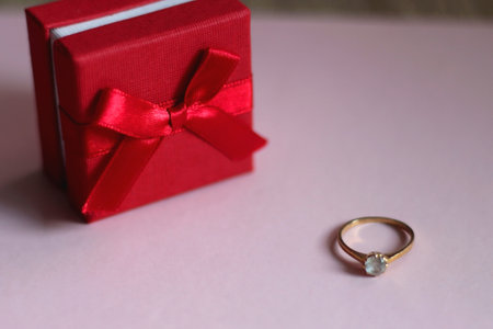 Engagement ring in elegant red box. Pink background, selective focus.