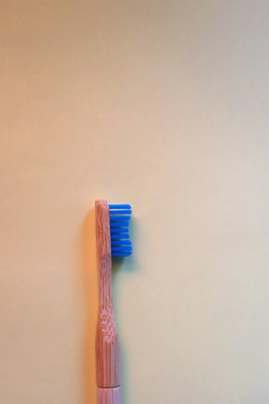Sustainable wooden toothbrush on pastel yellow background. Top view.