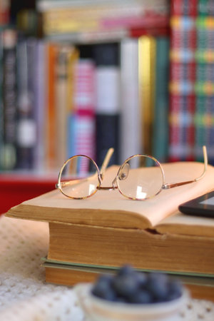 Plate of cookies, cup of tea, fresh blueberries, dry oranges, stack of books, reading glasses and tablet on the table. Hygge at home. Selective focus.の写真素材