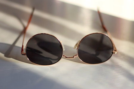 Retro round sunglasses on the table, illuminated by warm sunlight. Selective focus.の写真素材