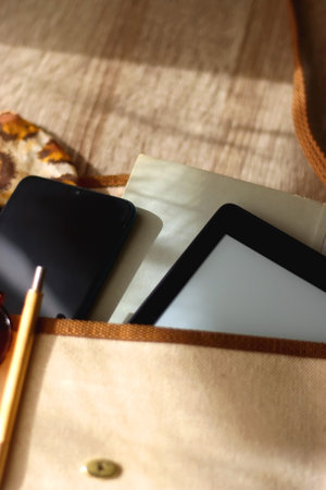 Retro bag with book, tablet, phone, pen, glasses and leopard pattern scarf. Selective focus, wooden background.の写真素材