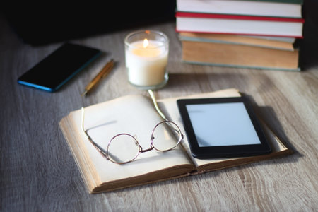 <p>Pile of books, tablet, reading glasses, mobile phone, scented candle, pen and laptop on the table. Selective focus.</p>の写真素材