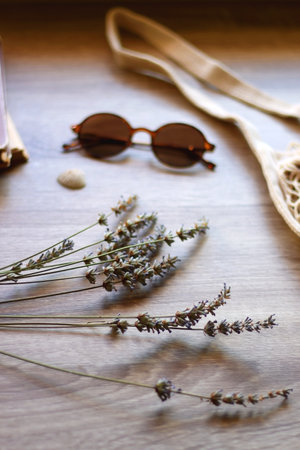 Mesh tote with fresh peacehs, lavender bouquet, round sunglasses, vintage book and seashell on the table. Selective focus.の写真素材