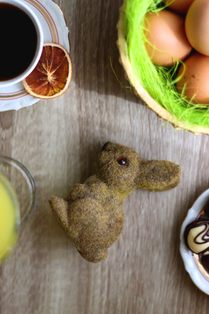 Easter eggs in the basket, bowl of cookies, chocolate pralines, Easter bunny figurine, cups of tea,...