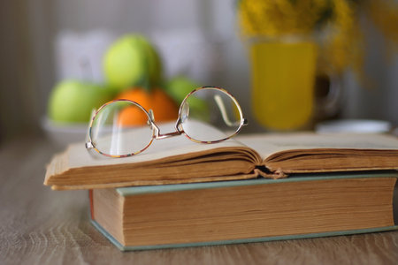 Cup of tea, plates with cookies, glass of orange juice, books, reading glasses, bowl of fruit and...