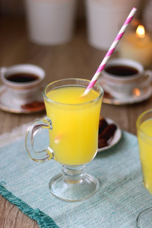 Plate of chocolate pralines, bowl of cookies, cups of tea, glasses of juice and lit candles on the table. Selective focus.の写真素材