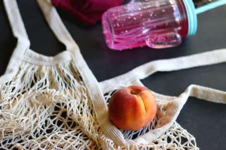 Pink bikini, cold soda, bag with peaches, sunglasses and little shell. Summer essentials on dark background. Selective focus.の写真素材