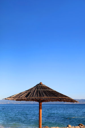Bamboo parasol on the beach. Bright blue sky and sea in the background. Selective focus.の写真素材