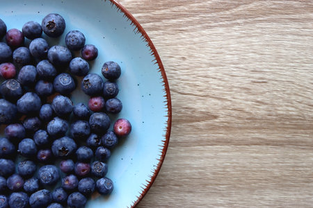 Turquoise plate with fresh blueberries on wooden background. Top view.の写真素材
