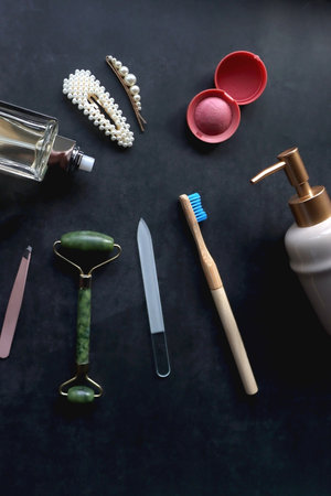 Perfume bottle, hair accessories, soap dispenser and various other beauty products on dark...