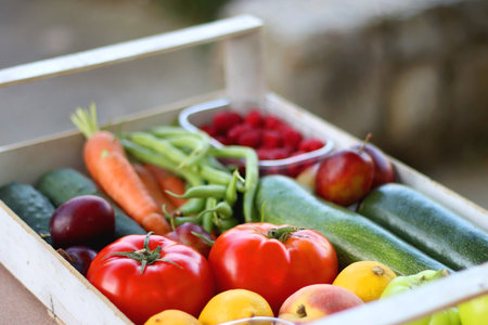 Wooden crate full of healthy seasonal fruit and vegetable, in the garden. Selective focus.の写真素材