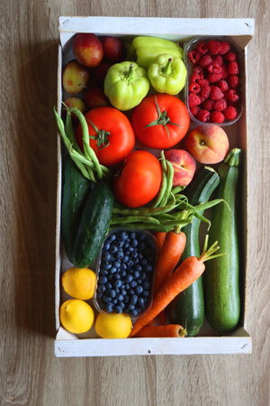 Wooden crate full of healthy seasonal fruit and vegetable. Top view, wooden background.の写真素材