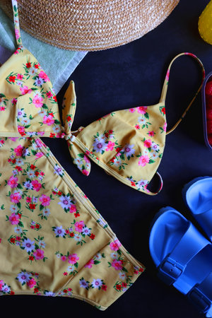 Floral swimsuit, striped towel, straw hat, cactus cup with orange soda, bowl of raspberries and blue...